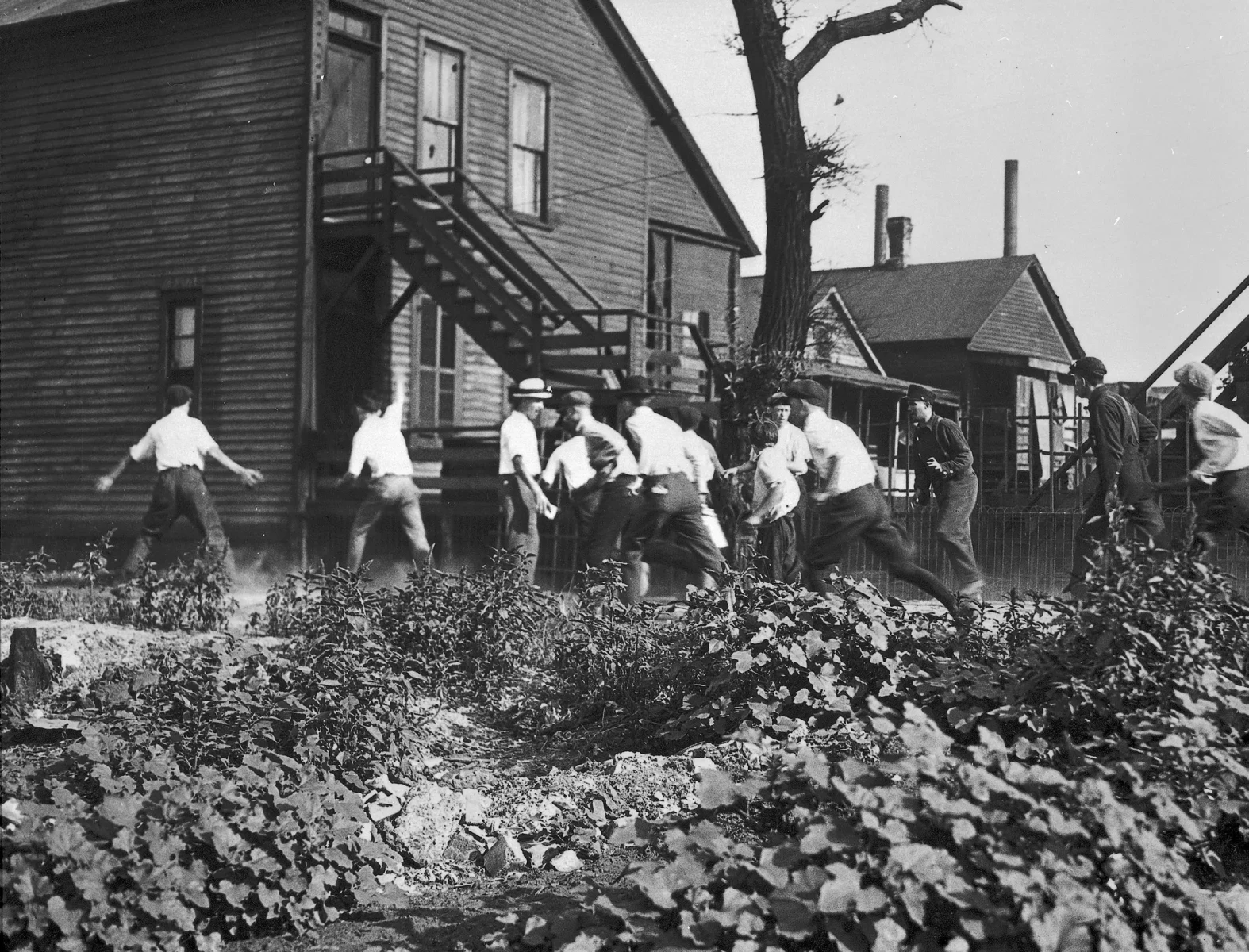 Uomini bianchi armati di mattoni e pietre inseguono un afro-americano durante la rivolta. 1919. (Jun Fujita/Chicago History Museum)